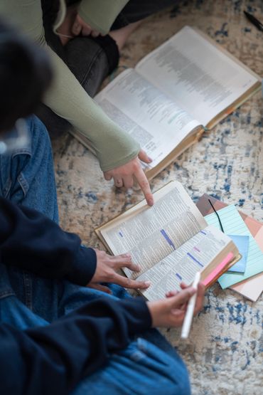 People reading and pointing at books on the floor.