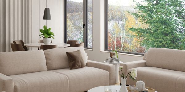 Bright living room with beige sofas and large windows showing autumn trees.
