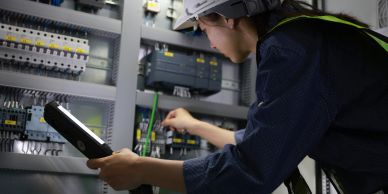 Woman electrician inspecting an electrical panel.