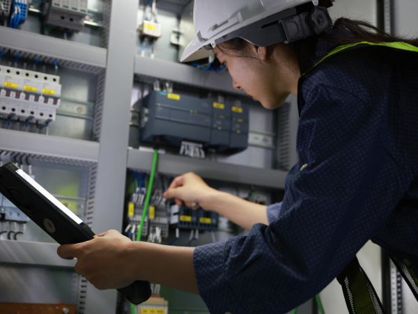 Electrician inspecting control panel with a flashlight.