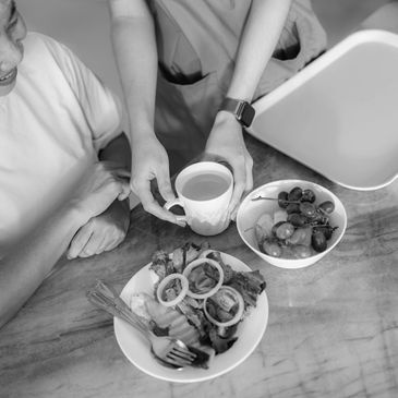 Person serving a cup of tea with salad and fruit on the table.