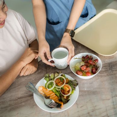 A delicious meal is being served - there is fresh fruit and salmon salad, and a mug of fresh water