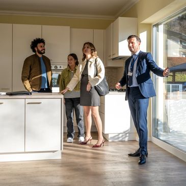 Real estate agent showing a kitchen to a family during a house tour.