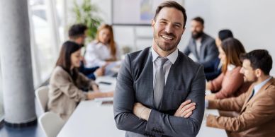 Smiling businessman standing confidently in office meeting room.