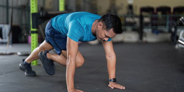 Man in blue shirt doing mountain climber exercise at gym.