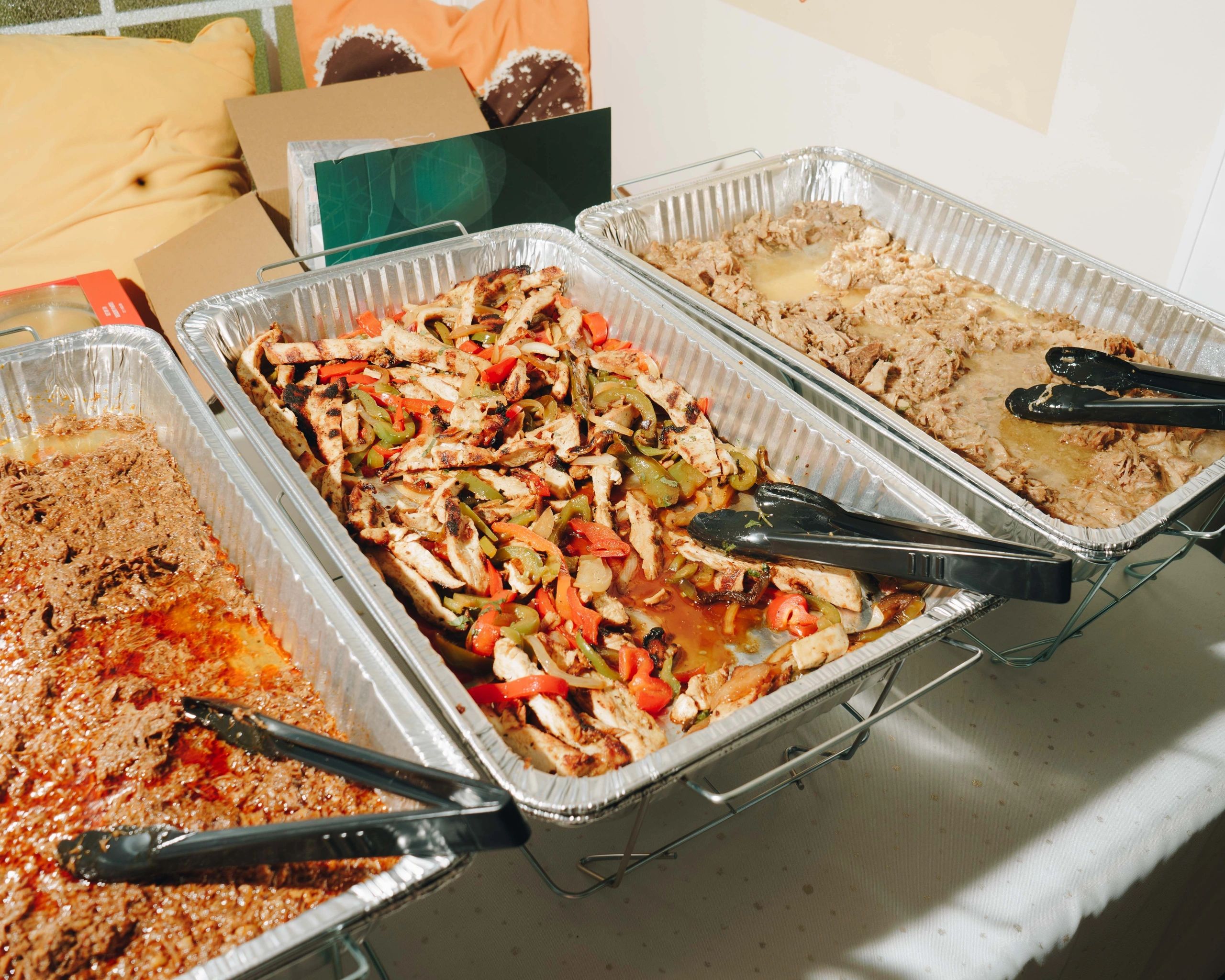 Latino-style catering trays with grilled chicken and fresh peppers.