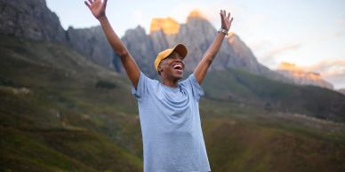 Joyful person with arms raised in scenic mountain landscape.