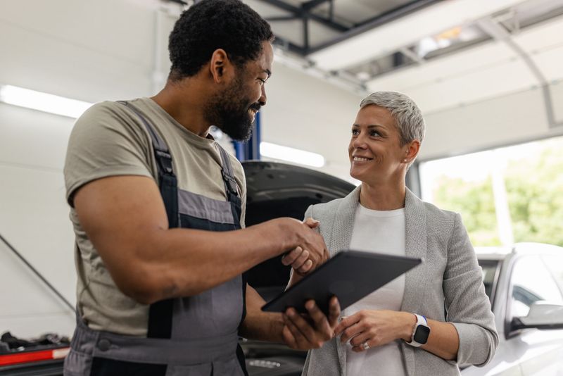 A mechanic and a businesswoman share a moment in an auto repair shop, emphasizing collaboration and professionalism in a service-driven environment.