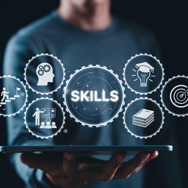 Person holding a tablet with digital skills icons floating above.