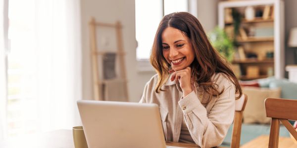 Woman smiling while using a laptop.
