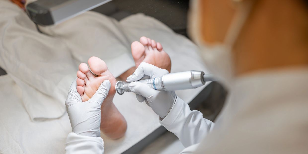 Professional pedicure treatment using an electric tool on feet.