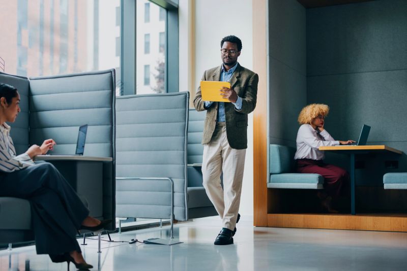 A professionally designed office space featuring individuals working on laptops and tablets, demonstrating productivity and collaboration in a modern workspace environment.