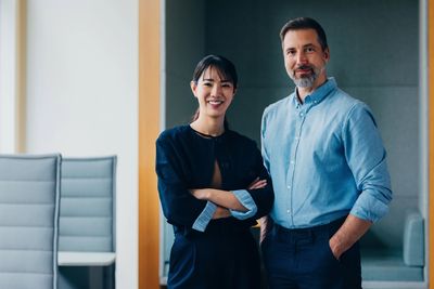 Two professionals smiling confidently in a modern office setting.
