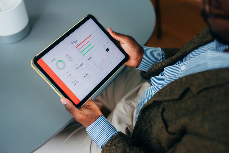 A business professional reviewing analytical data displayed on a tablet, depicting charts, graphs, and key figures. A professional setting emphasizing efficiency, technology, and decision-making in a modern business environment.
