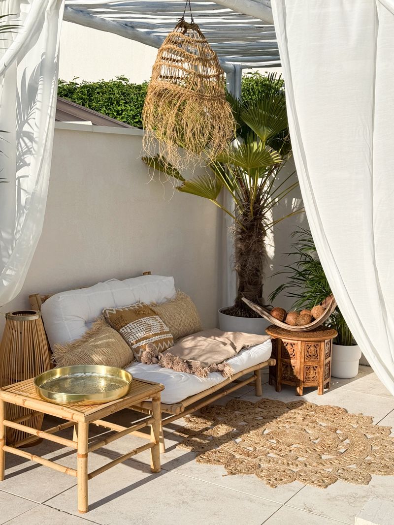 Boho bamboo outdoor sofa under driftwood pergola by the swimming pool in warm sunlight