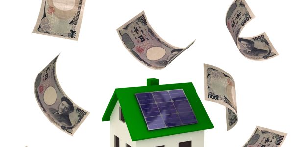 Model house with solar panels and flying Japanese yen bills around it.