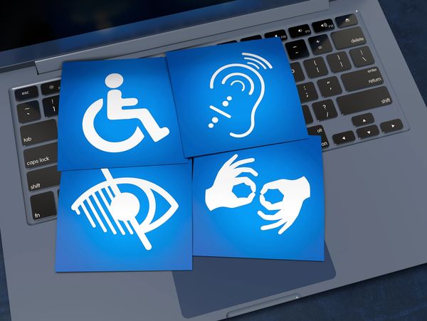 Accessibility icons for wheelchair, hearing, vision, and sign language on a laptop keyboard.