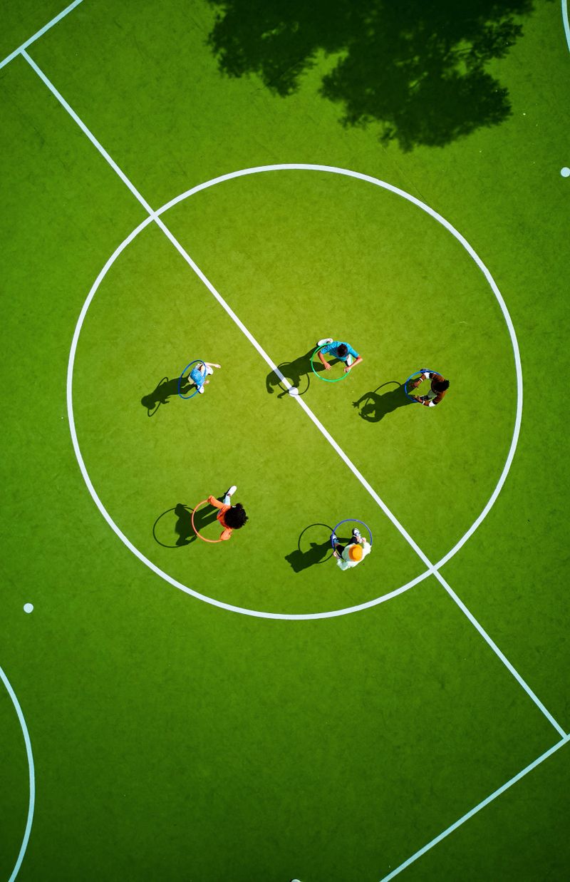 Aerial view of elementary age students having fun with hula hoops on a vibrant green school playground