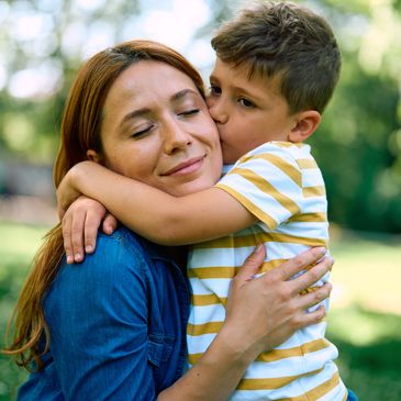 Mom hugging son; son giving mom a kiss on the cheek.