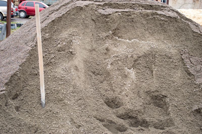 A large pile of sand sits at a construction site, ready for use in various building activities during the day.
