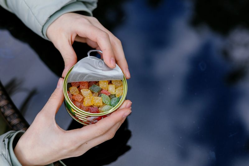 Colorful candy container showcases vibrant gummy treats by the waterside during a sunny afternoon
