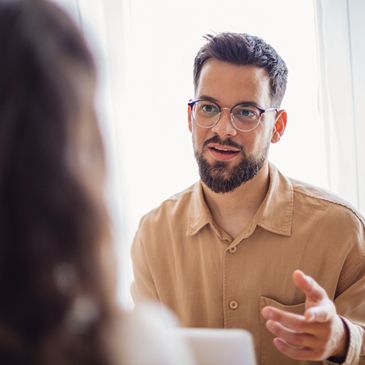 Man with glasses engaging in a conversation indoors.