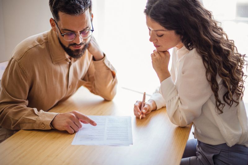 Two colleagues are carefully reviewing a document together, engaging in a productive discussion at their office