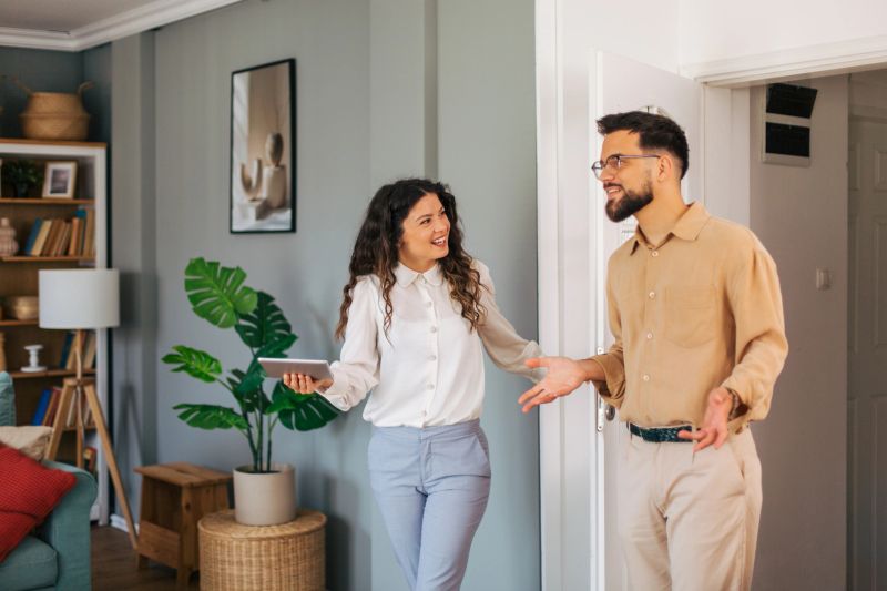 Real estate agent showing apartment to potential buyer using digital tablet