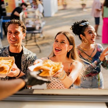 People happily receive fries at an outdoor food stall.