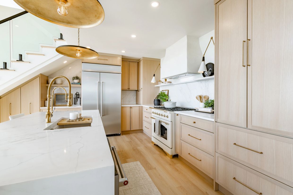 Modern kitchen with marble countertops and brass fixtures.
