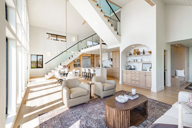 Interior rooms of an ocean front  home with floor to ceiling windows vaulted ceiling elegant spacious blue sky waterfront modern kitchen dining room entry foyer bedroom small home office area post and beam glass railing staircase loft bathrooms are white with marble granite and glass shower free standing bathtub modern appliances