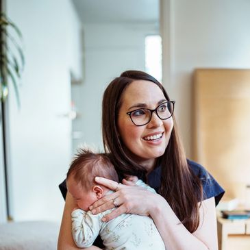 A smiling woman holding a newborn baby in a cozy home setting.