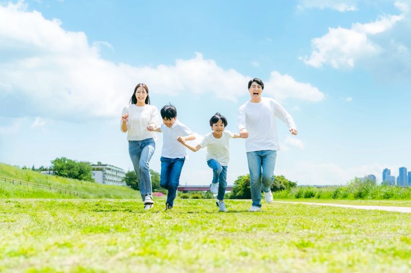 A family running on a meadow with blue sky