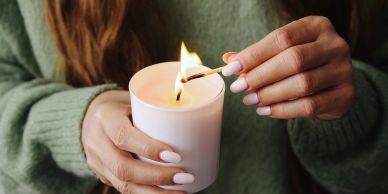 Person lighting a white candle.