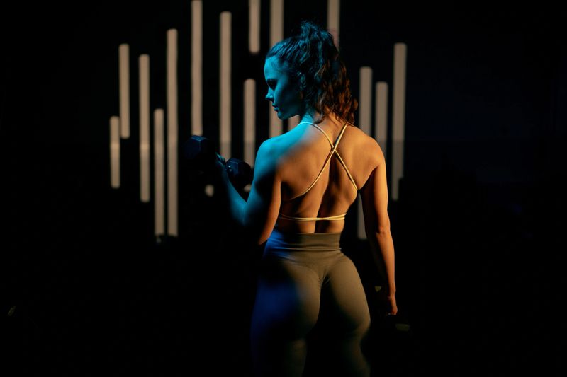 Young sportswoman stands strong in the dramatic lighting.