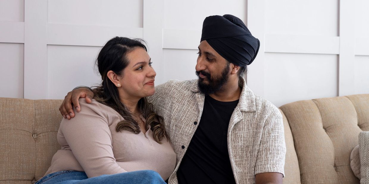 Couple sitting closely on a couch, sharing a warm moment.