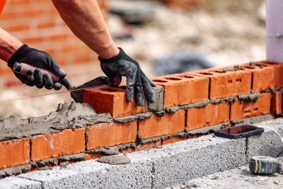 Worker laying bricks with mortar on a construction site.