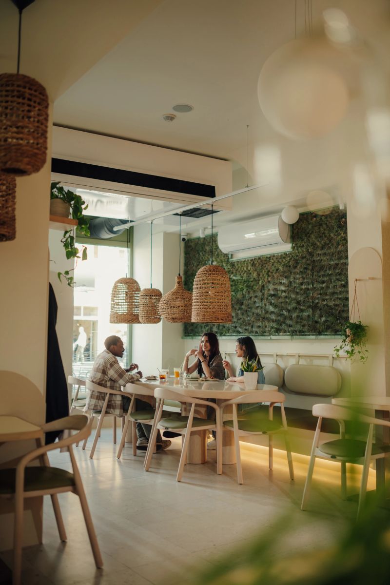 Three friends are sitting at a table in a modern restaurant, enjoying a meal and conversation together