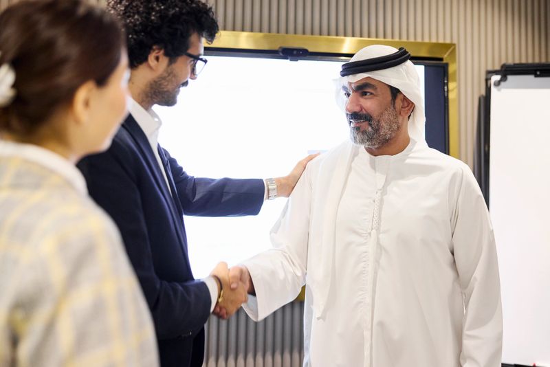 Arab businessman shaking hands after meeting. Male entrepreneur is congratulating partner for doing business deal in office. He is wearing religious outfit.