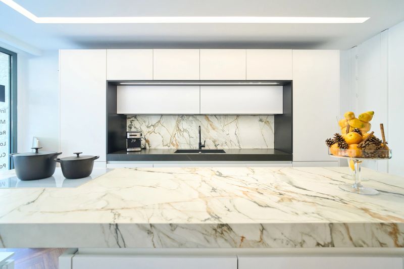 Luxurious kitchen showcasing a marble island, white cabinets, and modern appliances, creating a stylish and functional space