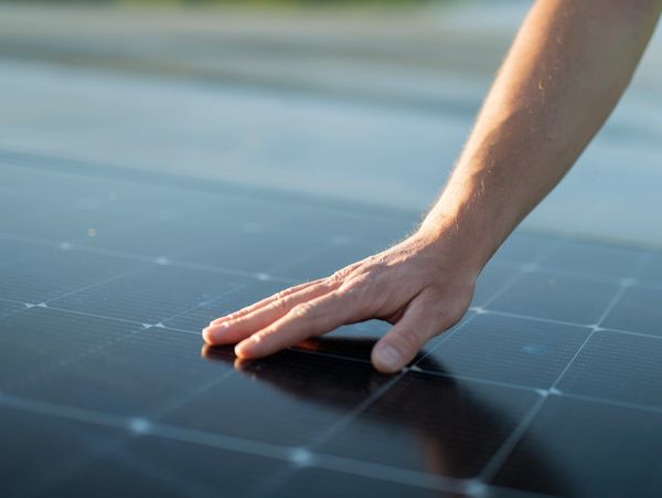 Hand touching a solar panel.