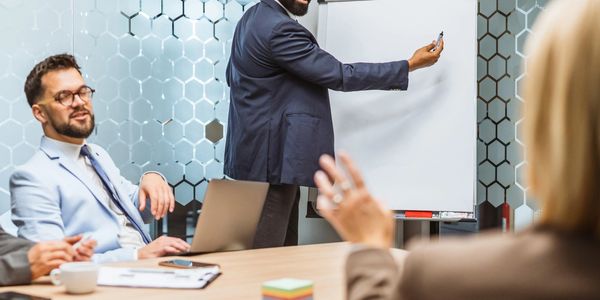Man in suit presenting with a flip chart in a modern office meeting.