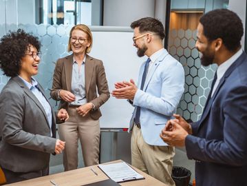 Four colleagues sharing a joyful moment during a meeting.