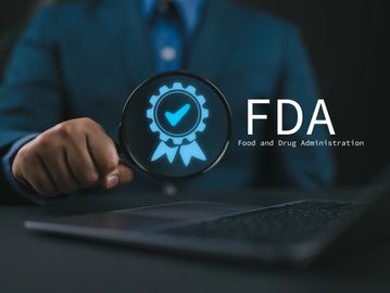 Magnifying glass highlighting FDA certification symbol by a person in a suit.