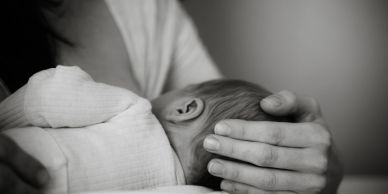 Mother lovingly holds a sleeping baby.