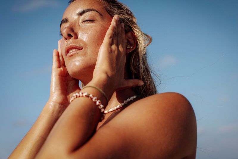 A serene woman with sun-kissed skin basks in the sunlight on a Maldives beach