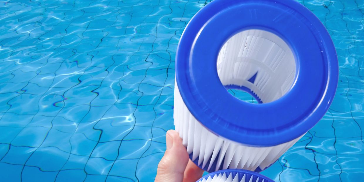 Close-up of a pool cartridge filter being held over a pool showing how clean they are