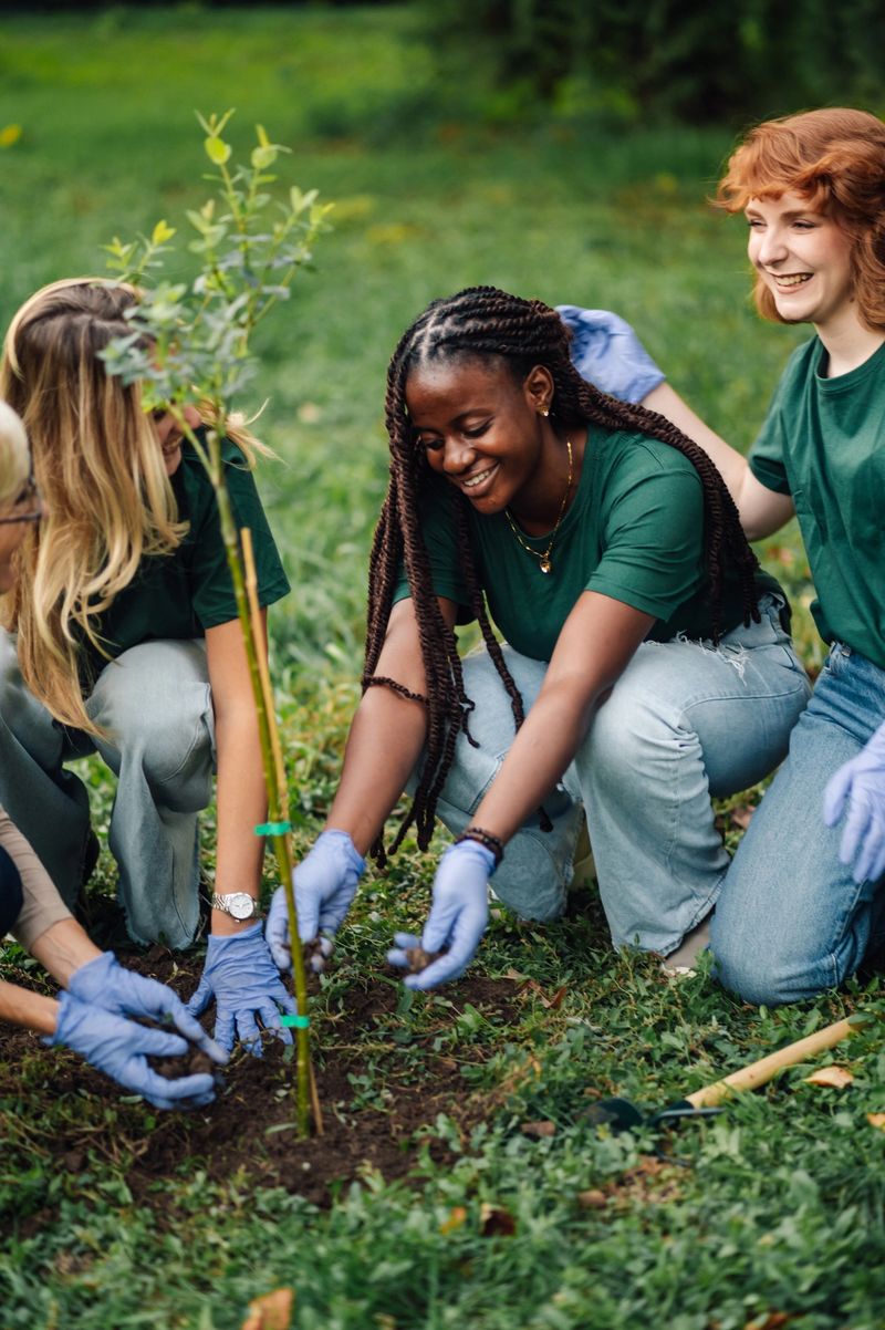 Group of multiethnic female volunteers planting a tree sapling in a park, working together for environmental conservation