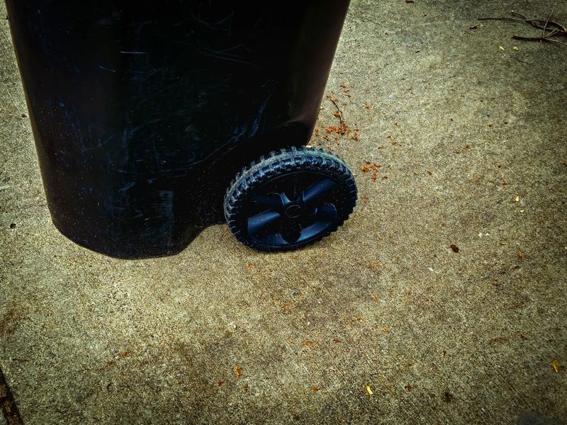 close-up of the bottom of a trash bin at the edge of a driveway curb