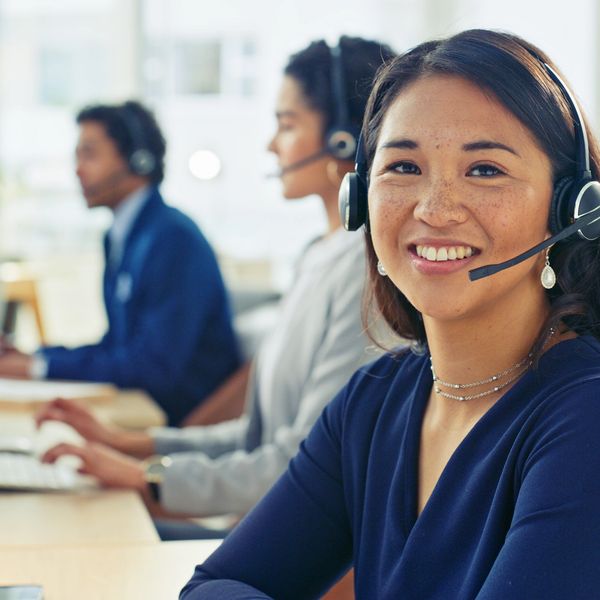 Smiling customer service representative wearing a headset in an office.